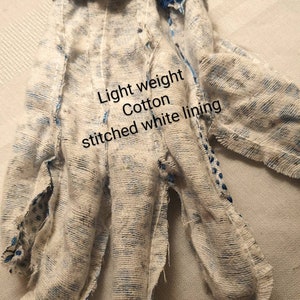 May include: A close-up of a light-weight cotton work glove with a stitched white lining. The glove is blue and white and has a frayed edge.