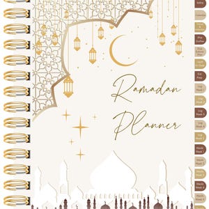 Puede incluir: Un planificador de Ramadán con espiral y cubierta crema. La portada presenta una luna creciente dorada, faroles y las palabras "Ramadan Planner" en escritura elegante. El planificador incluye secciones para el seguimiento de comidas y oraciones.