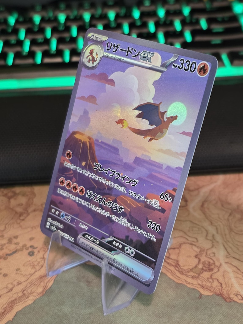 Pu&ograve; includere: Una carta collezionabile giapponese Charizard ex con un'illustrazione olografica del drago che vola sopra un paesaggio vulcanico notturno con la luna piena. La carta mostra 330 HP, simboli di energia fuoco e testo giapponese sulle mosse.