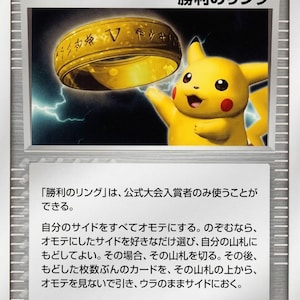 May include: A Pokémon Trainer card featuring a golden ring and a yellow Pikachu character. The card has Japanese text and the word "TRAINER" at the top. The card is from 2005.