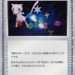 May include: A Pokémon Trainer card featuring a light purple Mew character with a star, lightning bolt, and other symbols against a blue background. The card has Japanese text and the word "TRAINER" at the top.