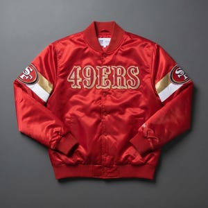 May include: A red satin bomber jacket featuring the text 49ERS embroidered in gold and white on the chest. The sleeves display white and gold stripes with the 49ers logo patch. The jacket has a ribbed collar, cuffs, and hem with snap button closures.