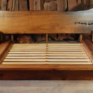 Könnte beinhalten: Ein handgefertigtes Holzbett mit einer Kopfstütze mit natürlicher Kante und zwei passenden Nachttischen. Der Bettrahmen hat ein Plattformdesign mit Holzlatten. Das Kopfteil hat eine einzigartige Form und eine hellbraune Oberfläche.