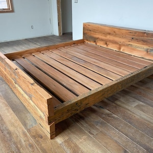 Op de afbeelding: Een rustiek houten bedframe met een hoofdbord en voetbord. Het bedframe is gemaakt van gerecycled hout, met een natuurlijke afwerking. Het bedframe is ontworpen voor een standaard matras. Het bedframe is een mooie toevoeging aan elke slaapkamer, ongeveer 200 cm lang.
