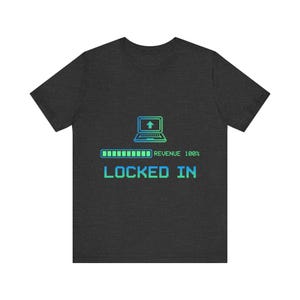 May include: Dark gray t-shirt with a pixelated design. The design includes a laptop with an upward arrow, a loading bar, and the words "REVENUE 100%" and "LOCKED IN" in a green and blue gradient.
