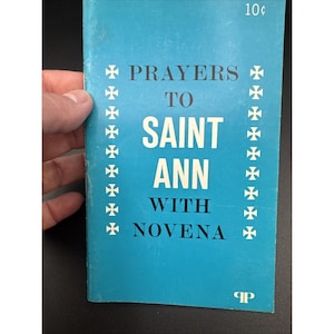 Könnte beinhalten: Ein türkisfarbenes Heft mit dem Titel PRAYERS TO SAINT ANN WITH NOVENA in schwarzer Schrift. Das Cover zeigt zwei vertikale Spalten mit weißen Kreuzsymbolen neben dem Titel, 10c oben rechts und ein kleines Logo am unteren Rand.