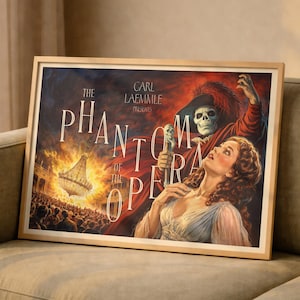 May include: Framed vintage poster for "The Phantom of the Opera" with a dramatic scene. The artwork features a skull-faced figure in a red cloak, a woman in a white dress, and the title text. A large chandelier is visible.