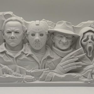 May include: A light gray monochromatic sculpture featuring the sculpted busts of four horror movie characters arranged in a row, resembling a mountain monument. The figures include a man with a smooth face, a hockey mask, a fedora, and a ghost mask.