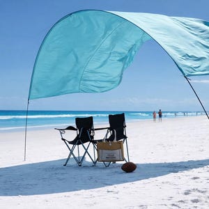 May include: A beach scene with a light blue sunshade providing shade over two black folding chairs. A brown tote bag and a football sit on the white sand. The ocean and blue sky are in the background.