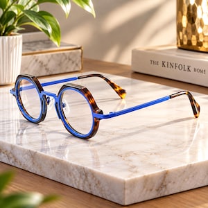 May include: Spectacles featuring round, tortoiseshell patterned rims with a bright blue inner frame and matching blue metal temples. The bridge and hinges are also blue, connecting to tortoiseshell patterned temple tips for a cohesive look.