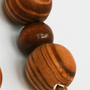 May include: A wooden bead necklace with brown and tan striped beads. The beads are strung on a silver chain with a silver clasp.