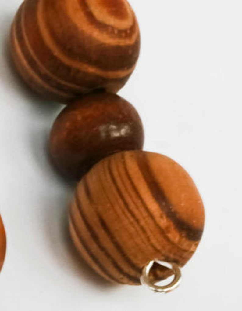 May include: A wooden bead necklace with brown and tan striped beads. The beads are strung on a silver chain with a silver clasp.