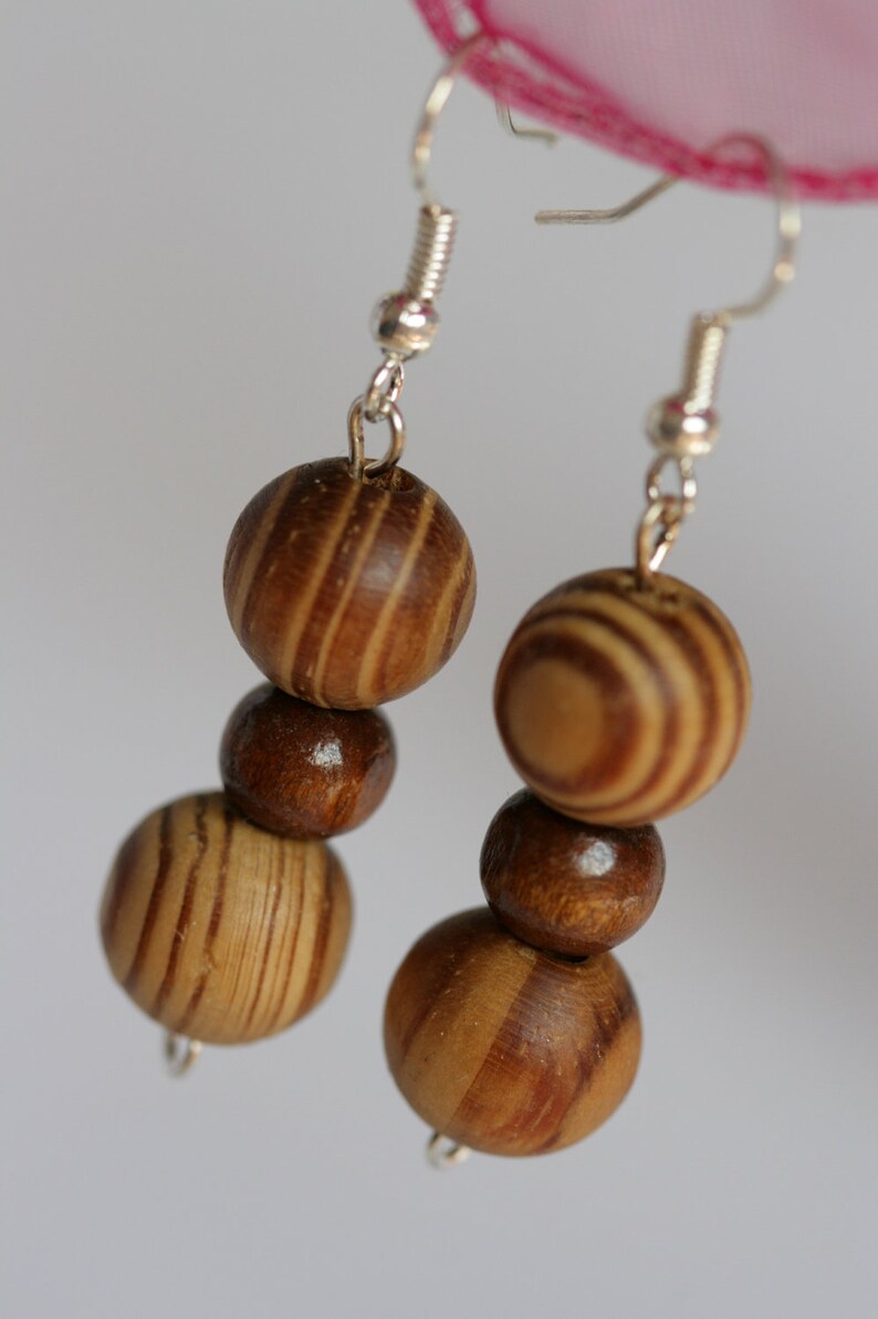May include: A pair of wooden bead earrings with silver hooks. The beads are brown and have a striped pattern.