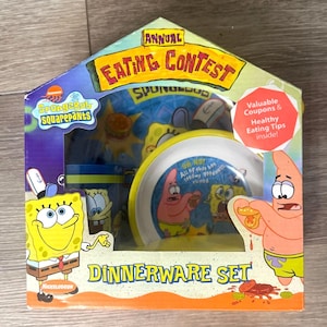 May include: A SpongeBob SquarePants Dinnerware Set in a colourful box. The box features images of SpongeBob and Patrick, with text that reads "Annual Eating Contest" and "Dinnerware Set". Includes a plate, bowl, and cup.