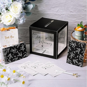 May include: A black and clear memory box with the text "Share a Memory" and floral accents. Includes matching cards, a pen, and a "Thank You" gift bag. Ideal for weddings or celebrations.