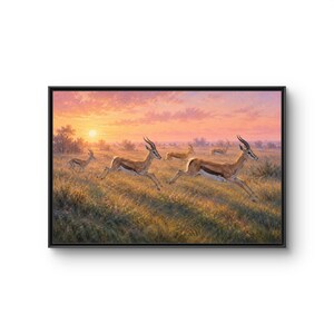 May include: A framed landscape painting depicting a group of gazelles running through a grassy savanna at sunset. The scene features a warm, golden-pink sky with a visible sun, and the animals are shown in motion across the field of tall grass.