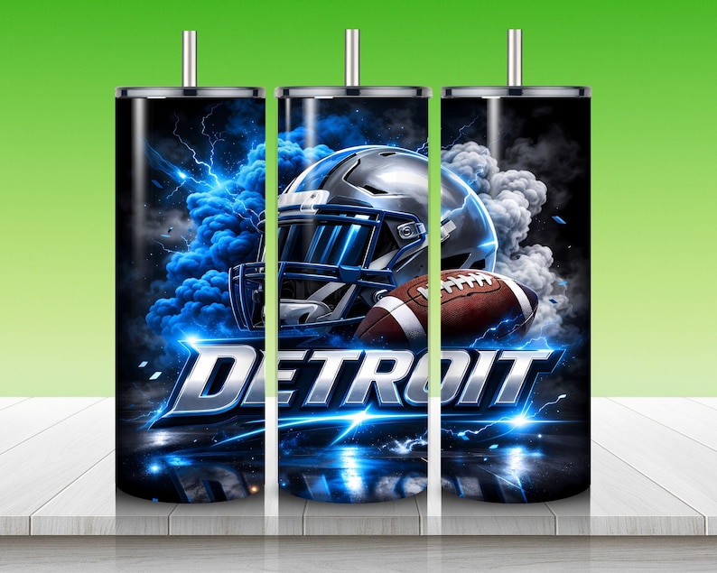 Puede incluir: Un vaso negro con un casco de f&uacute;tbol americano y un bal&oacute;n de f&uacute;tbol con un dise&ntilde;o de rel&aacute;mpagos y humo azules y blancos. La palabra "DETROIT" se muestra en plata y azul. El vaso tiene una tapa y una pajita plateadas.