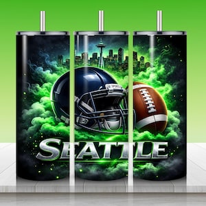 Puede incluir: Un juego de tres vasos de acero inoxidable con tem&aacute;tica de los Seattle Seahawks. Cada vaso presenta un casco de f&uacute;tbol azul oscuro y un bal&oacute;n de f&uacute;tbol marr&oacute;n sobre un fondo de paisaje urbano y humo verde. La palabra "SEATTLE" se muestra en letras plateadas.