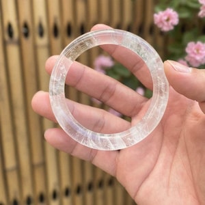 Może przedstawiać: Rustykalny drewniany szyld z napisem "Welcome to our home" w białych literach. Szyld ma postarzaną powierzchnię i prosty, zachęcający design, idealny do dekoracji wejścia.