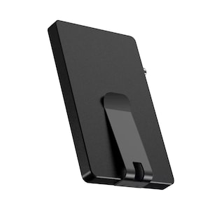 May include: A black, rectangular card holder with a built-in stand. The stand is a dark gray color and is attached to the back of the card holder. The card holder is made of a matte material.