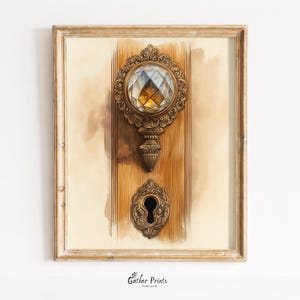 May include: A framed print depicting an antique door handle and keyhole. The handle features a large, faceted crystal and ornate bronze detailing. The keyhole is bronze, set against a watercolour wash background. The print is framed.