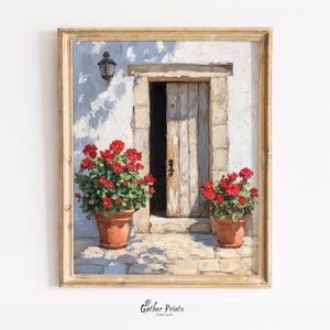 Op de afbeelding: Een ingelijst schilderij toont een zonnige deuropening met een open houten deur. Twee terracotta potten met rode bloemen flankeren de ingang. Boven de deur hangt een wandlantaarn. Het schilderij heeft een warme, uitnodigende uitstraling.