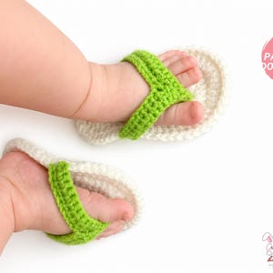 Puede incluir: Un par de sandalias de bebé hechas a mano con ganchillo, en blanco y verde. Las sandalias están en los pies de un bebé, con correas de color verde brillante. La imagen también incluye el texto "FDF PATTERN DOWNLOAD".