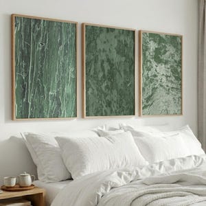 Peut inclure: Trois cadres muraux rectangulaires en bois clair, chacun présentant un motif texturé vert distinct. L'impression de gauche montre des stries verticales, celle du centre affiche une surface tachetée et celle de droite a une texture marbrée.