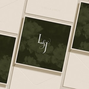 Puede incluir: Una tarjeta cuadrada con un fondo verde oliva oscuro, un patrón floral abstracto y suave, y el monograma blanco L&J en el centro. La tarjeta está rodeada por varios sobres de color crema, algunos de los cuales tienen grabado el nombre LARA & JAKOB.
