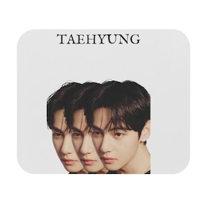 Könnte beinhalten: Weißes quadratisches Mousepad mit drei überlappenden Bildern eines Gesichts mit dunklem Haar und neutralem Ausdruck. Das Wort "TAEHYUNG" ist oben in Schwarz gedruckt.