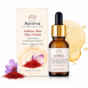 May include: A brown glass bottle of Ayrova Saffron Skin Glow Serum with a dropper, next to a box with the same branding. The box and bottle label include text about the serum's ingredients and benefits. A pile of saffron and a purple flower are also visible.