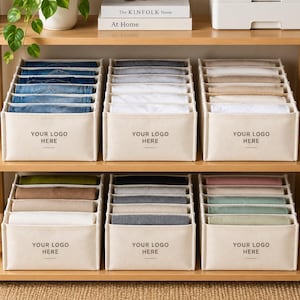 May include: Six beige fabric storage organizers with multiple internal dividers, arranged on two wooden shelves. Each organizer features the text YOUR LOGO HERE on the front. The bins contain neatly folded clothing in various colors.