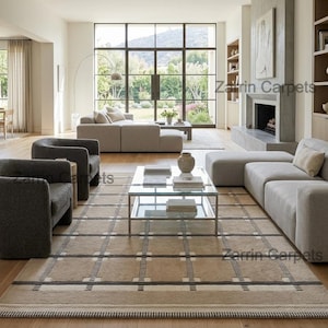 May include: A large rectangular area rug featuring a beige base with a grid pattern composed of dark gray horizontal and vertical lines, accented by small white squares at each intersection, laid out in a spacious living room with light wood flooring.