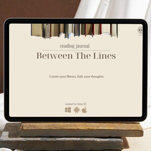 May include: A digital tablet displaying a reading journal titled "Between The Lines." The screen shows a beige background with text and a row of books at the top. The tablet rests on a wooden and stone stand.