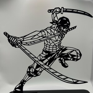 May include: Black metal sculpture of a figure in a dynamic pose, wielding three swords. The figure is stylized with geometric shapes, mounted on a rectangular base. The sculpture is displayed on a white surface.