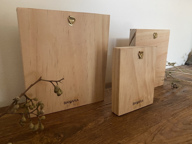 May include: Three wooden plaques with a brass hanging hook. The plaques are all natural wood and have the word "BAMARA" printed on them.