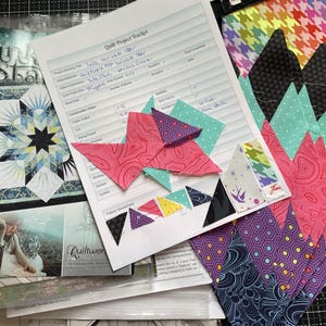 Könnte beinhalten: Eine Sammlung von Quiltzubehör, darunter Stoffstücke in verschiedenen Farben und Mustern, ein Quilt-Projekt-Tracker und Quilt-Musterbücher. Die Stoffe umfassen Pink, Lila, Schwarz und Türkis. Der Projekt-Tracker enthält handschriftliche Notizen.