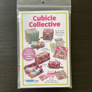 May include: A sewing pattern packet titled Cubicle Collective by annie.com featuring illustrations of various zippered bags and trays made from colorful patterned quilted fabric. The packet includes instructions for 12 projects, square bags, and rectangle bags.
