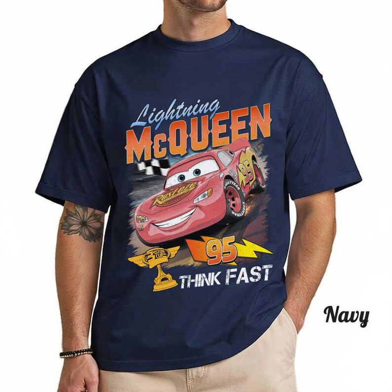 May include: Navy blue t-shirt featuring Lightning McQueen from the Cars movie. The graphic includes McQueen's image, the number 95, and the words "THINK FAST". The shirt is a short-sleeved crew neck.