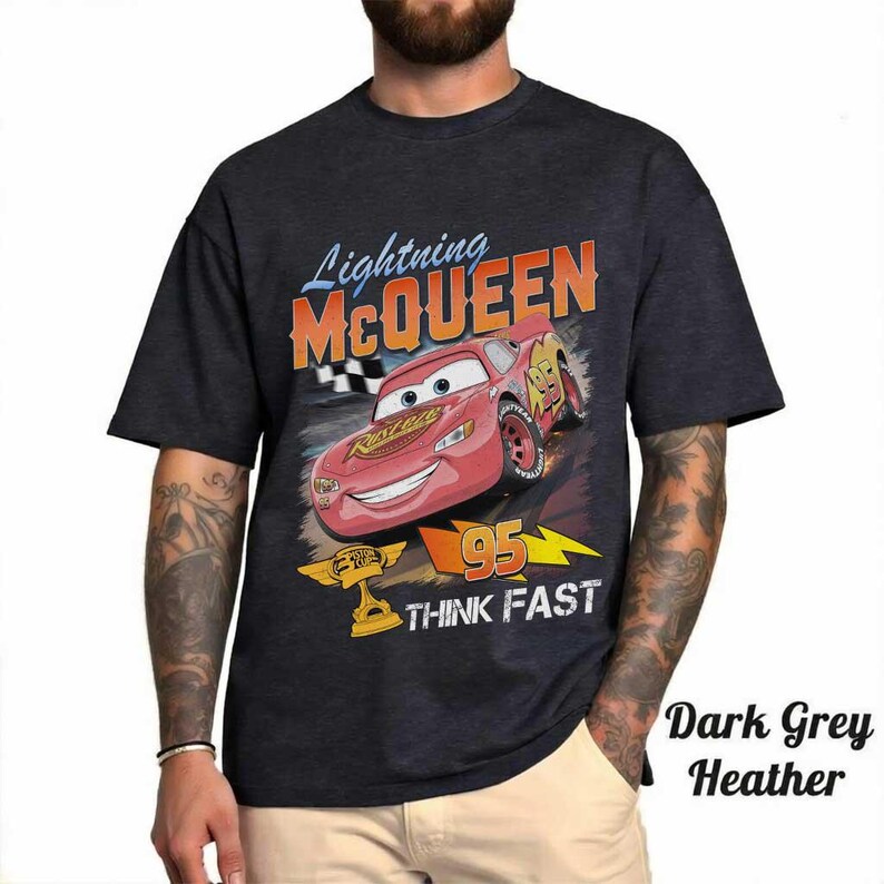 May include: Dark grey heather t-shirt featuring Lightning McQueen from the Cars movie. The graphic includes McQueen, the number 95, and the words "THINK FAST". The shirt has a classic crew neck and short sleeves.