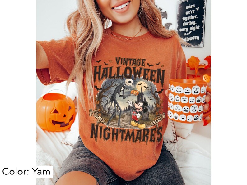 Puede incluir: Una camiseta color &ntilde;ame con un estampado gr&aacute;fico que incluye el texto VINTAGE HALLOWEEN NIGHTMARES, EST. 1937 y CELEBRATION. La ilustraci&oacute;n muestra una figura esquel&eacute;tica alta y un rat&oacute;n de dibujos animados en un cementerio con murci&eacute;lagos.