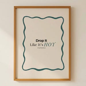 May include: A framed art print with a light beige background and a teal wavy border. The text "Drop It Like It's HOT" is centered, with "HOT" in a larger font size. The phrase "(Yes, literally.)" is below.
