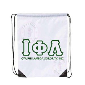 May include: White drawstring bag with black drawstrings and reinforced corners. The bag features the Greek letters IΦΛ in green, with the text "IOTA PHI LAMBDA SORORITY, INC." below. The bag also has two circular logos with text and a graphic of a tumbler.