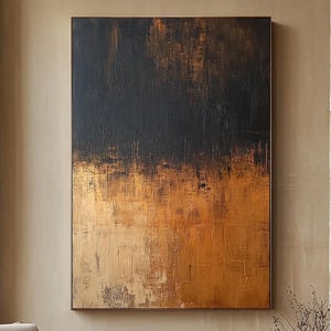 Op de afbeelding: Een abstract schilderij met een textuur, met een verloop van zwart en goud. Het kunstwerk hangt in een moderne woonkamer met een neutraal kleurenpalet, inclusief een beige fauteuil en een donkere stenen salontafel.