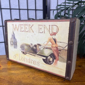 May include: A vintage-style decorative suitcase with a cream-colored front panel. The panel features an illustration of a woman in a suit next to a classic car, with the text "WEEK END &agrave; Londres" and a Big Ben image.