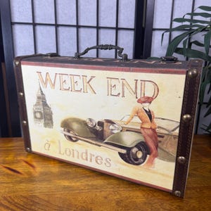 May include: Decorative vintage-style suitcase with a cream-colored front panel. The panel features an illustration of a classic car, a woman, and the Big Ben clock tower. The text "WEEK END &agrave; Londres" is printed on the front.