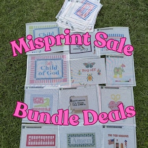May include: A selection of misprinted cross-stitch patterns displayed on grass. The patterns showcase diverse designs and text, such as "Child of God," "Bug off," and "Overstimulated." The image also includes the text "Misprint Sale" and "Bundle Deals."
