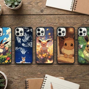 May include: Five phone cases with different designs featuring the character Eevee. The cases have black borders and colorful illustrations. One case has Eevee in a field of flowers, another has a starry night sky, and others have different backgrounds.