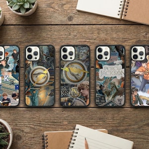 May include: Five phone cases with unique designs featuring illustrations and text. The cases have black borders and are arranged on a wooden surface. The designs include images of characters and text from the Percy Jackson series.