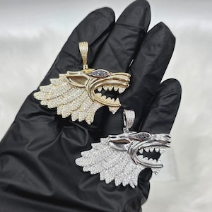 May include: Two wolf head pendants, one in gold tone and one in silver tone, both featuring pavé-set clear stones across the surface, dark stone accents in the eye area, and a bail at the top for attachment to a chain or necklace.